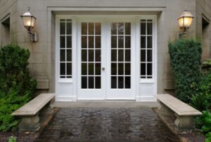 White entry doors to a home with sconce lighting