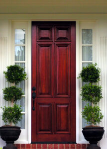 Wooden front door on suburban home with plants in front