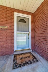 Storm door on a brick home with a welcome mat