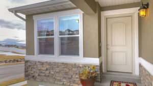 White front door and reflective window of a home against road and cloudy sky